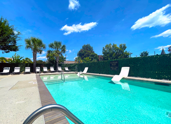 a swimming pool with chaise lounge chairs and trees in the background